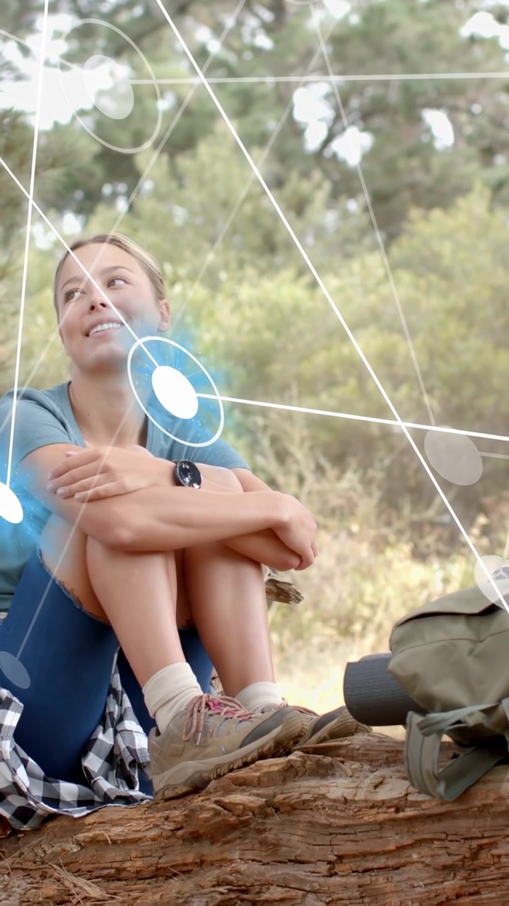 Video verticale: Donna seduta su un tronco che segue la tecnologia AR che appare con un nodo pulsante sul petto, sorridendo.