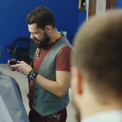stylish male stylist cutting hair for bearded client
