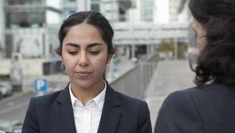 businesswomen with papers and smartphone on street