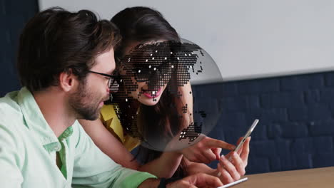 animation of spinning globe over colleagues male and female colleagues discussing at office