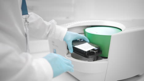 un asistente de laboratorio coloca muestras bajo un innovador microscopio electrónico para la investigación farmacéutica en ciencias biológicas