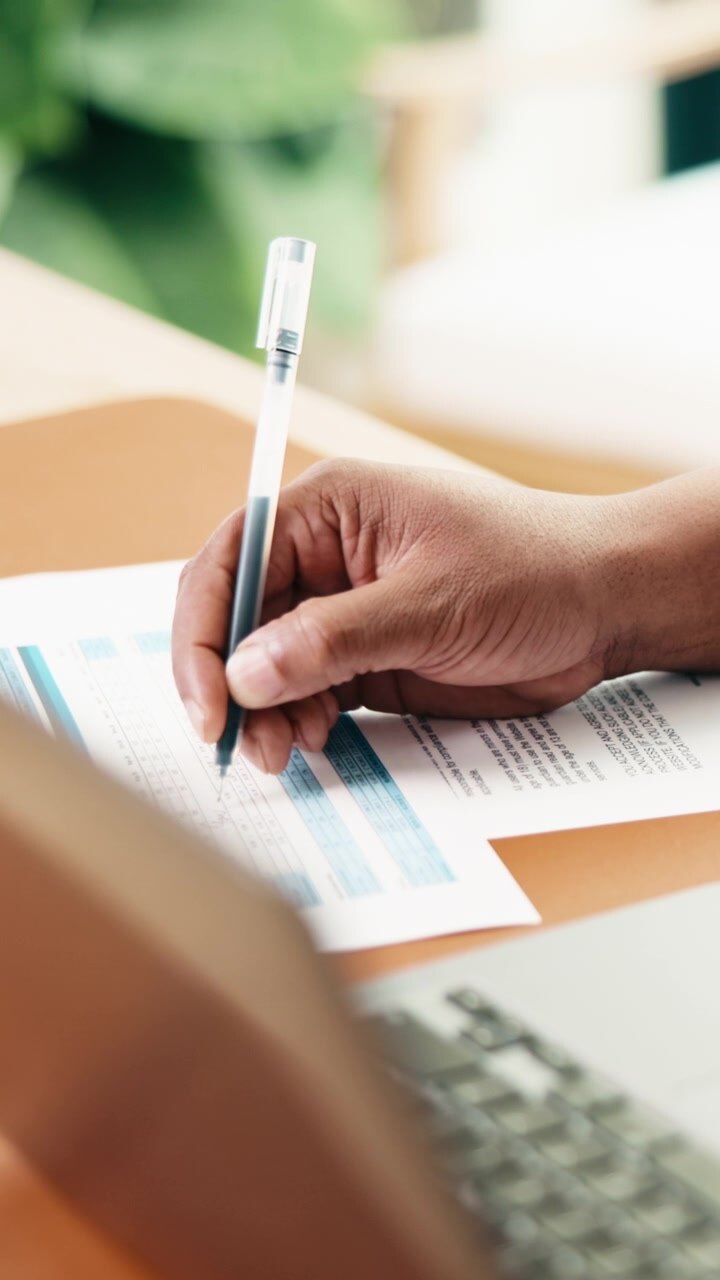 Person Writing on Document at Desk in Office