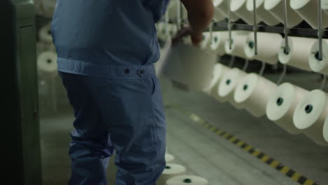 factory worker brings new cotton bobbins to the cotton textile winding machine in a factory in china