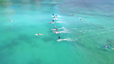 surfers in a line riding the waves of waikiki beach,honolulu,hawaii