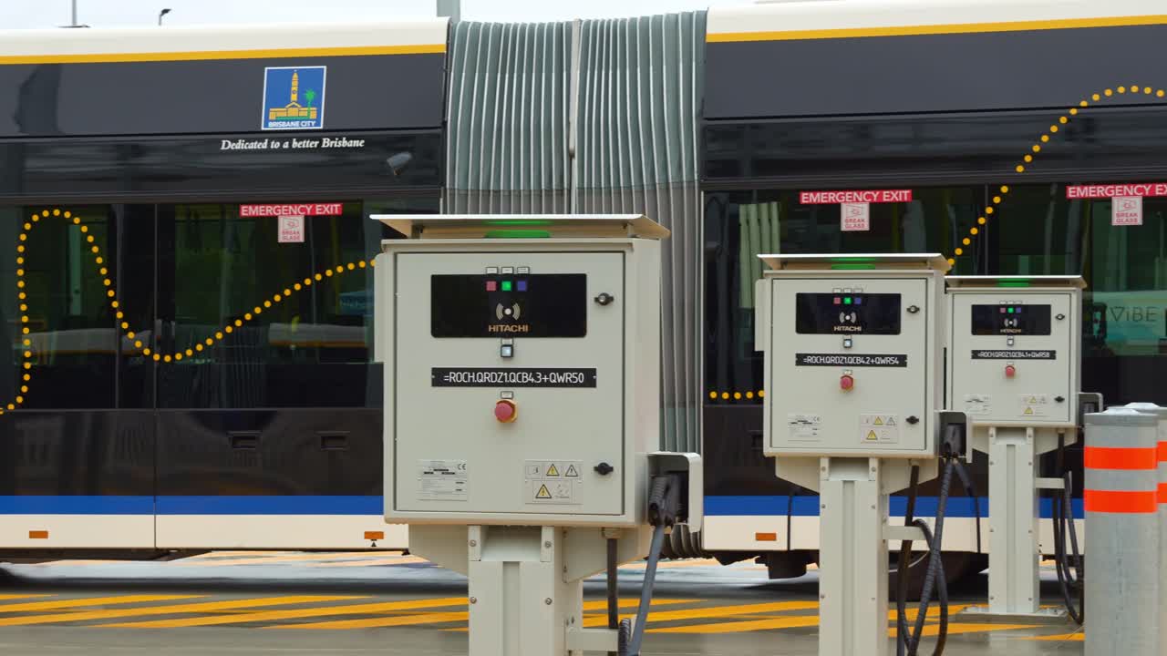 Electric bi-articulated vehicle, Metro bus parked at the off-peak slow charging station in Rochedale depot, innovative bus rapid transit system in Queensland, panning shot.