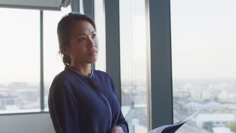 thoughtful professional businesswoman looking out of a window while her hand on her chin in slow mot