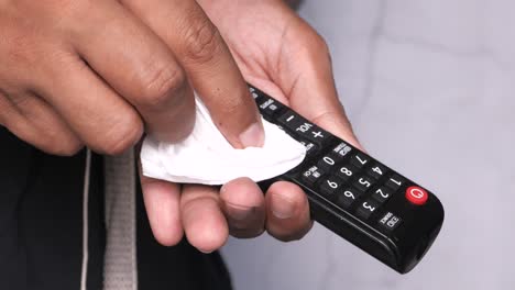 cleaning a tv remote with a tissue