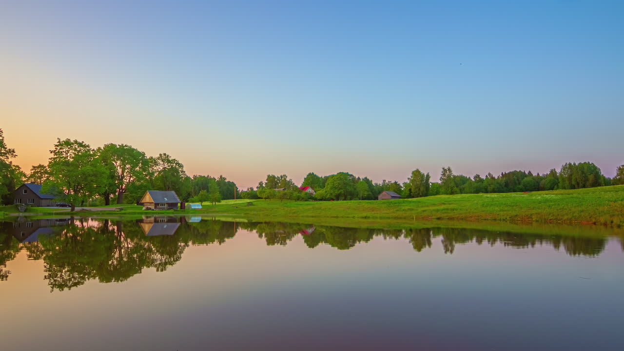 아름다운 조용한 호수 위의 일몰의 영화적인 영상과 배경에는 집과 나무가 있고 하늘은  ⁇ 고 아름다운 색 변화, 타임  ⁇ 스, 타임  ⁇ 스