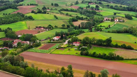 Tight aerial drone push-in of charming farmhouses and cultivated fields in Tuscany, Italy (Toscana), with a scenic rural countryside atmosphere