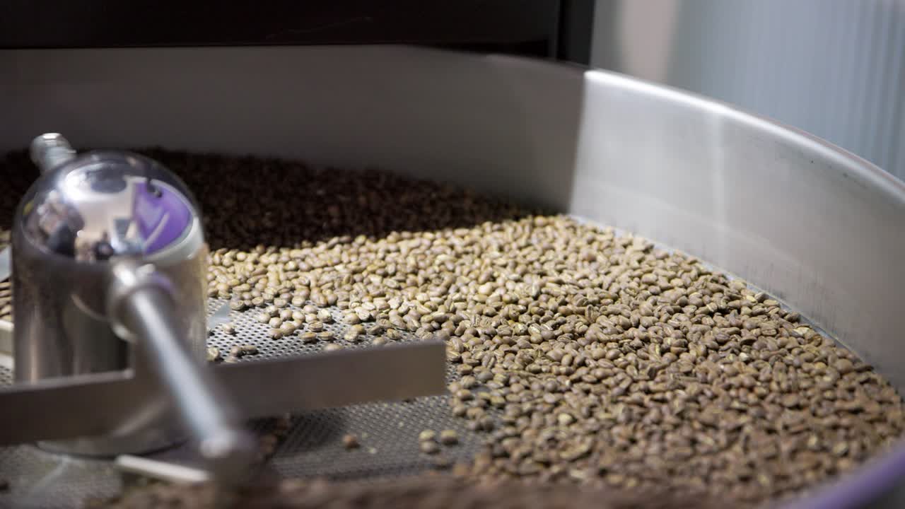 Metal rotating skimmer pushes and tumbles coffee beans through drum machine
