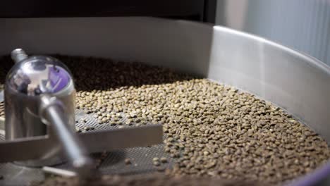 metal rotating skimmer pushes and tumbles coffee beans through drum machine