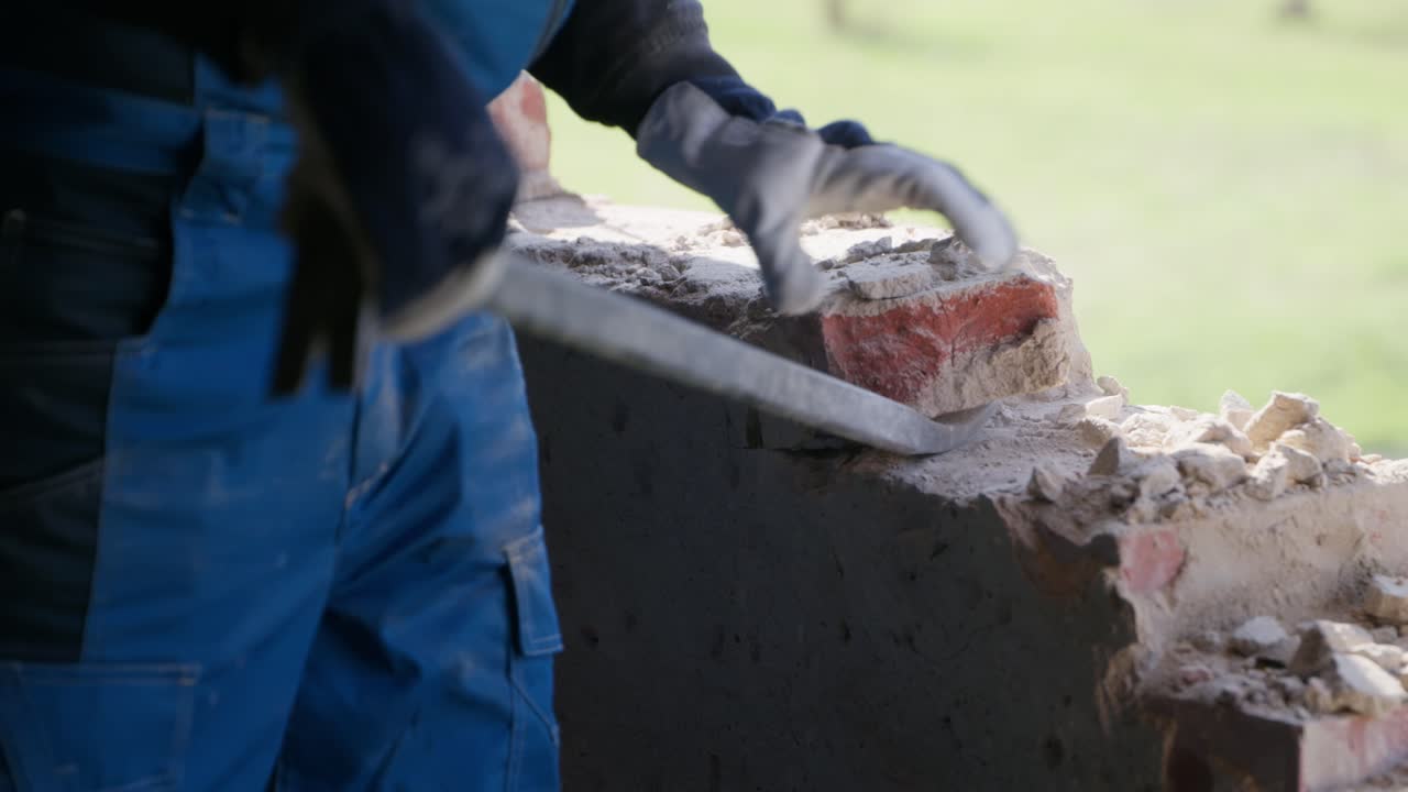 집 해체 현장, 오래된 벽돌을 제거하기 위해 지렛대를 사용하는 인식할 수 없는 작업자