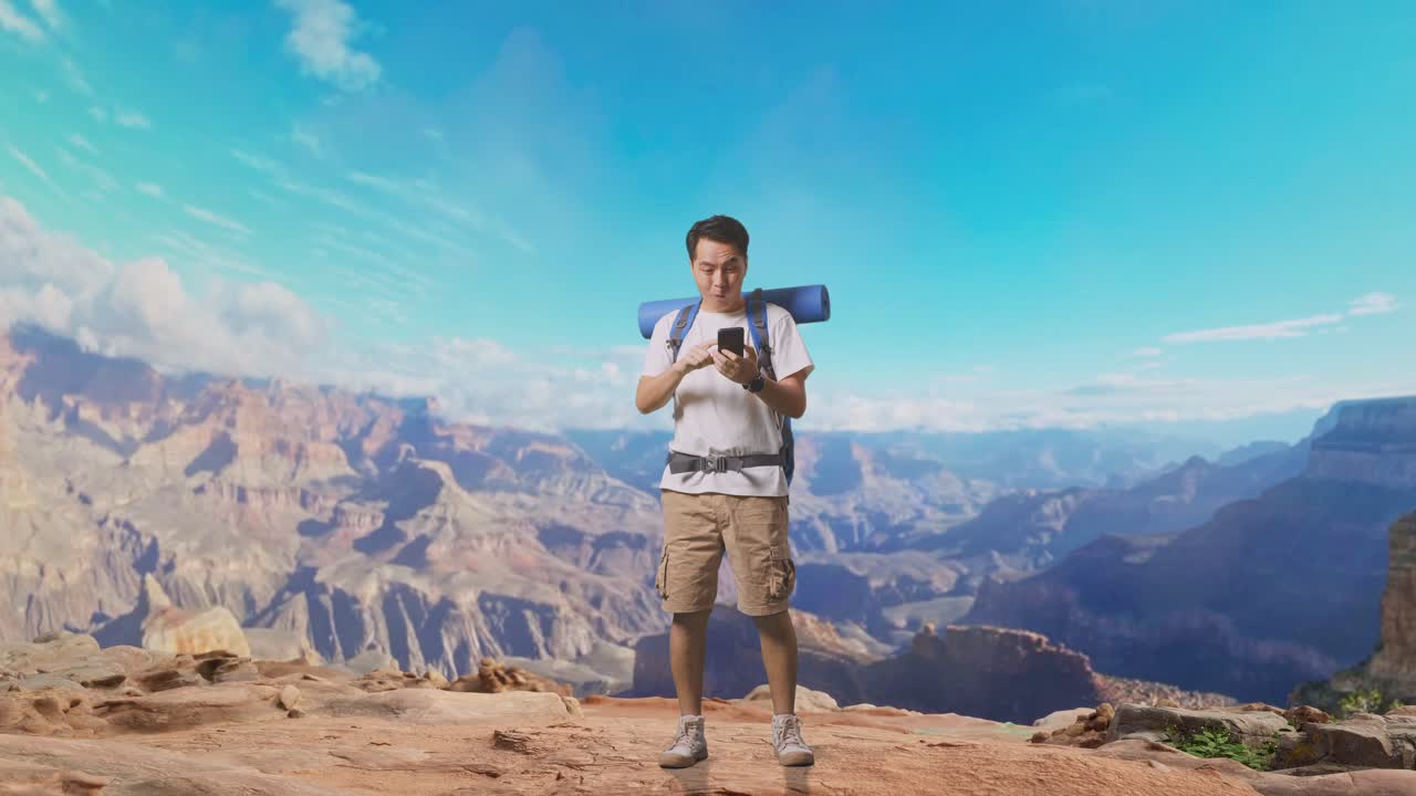 Full Body Of Asian Male Hiker With Mountaineering Backpack Looking At The Smartphone And Screaming Goal Celebrating The Success While Traveling At The Top Of Mountain