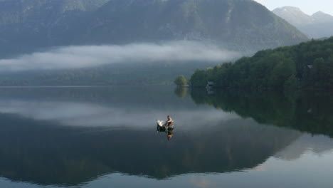 local fisherman on boat floating at calm waters of bohinj lake in slovenia