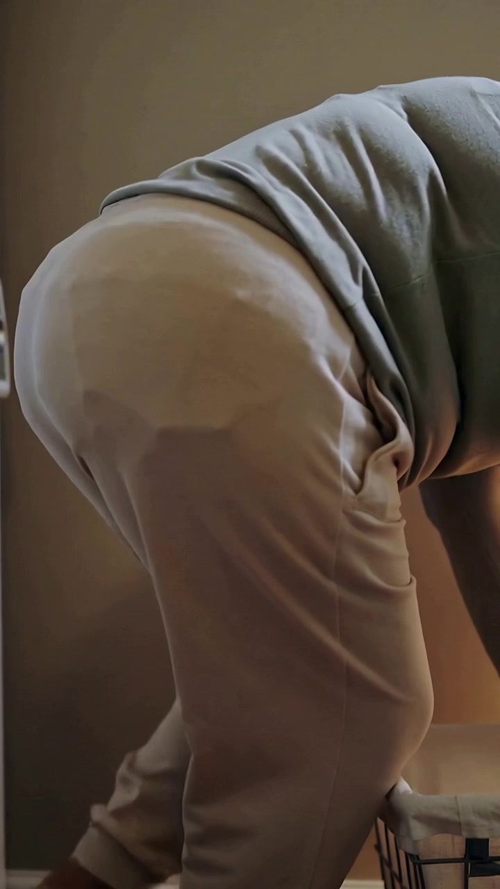 Video verticale: Adulto in maglione che tira i vestiti da un cesto della biancheria pieno e foderato, smistando il bucato a casa.