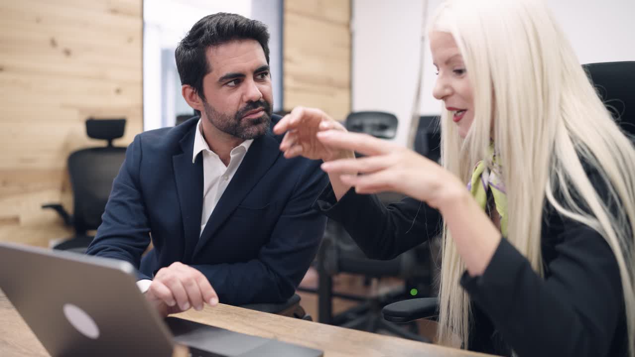 To forretningskolleger diskuterer arbejde på et moderne kontor