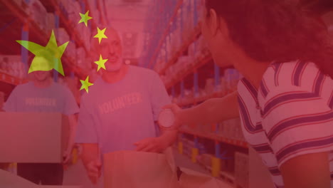 animation of flag of china over diverse male volunteers and woman making donation in warehouse