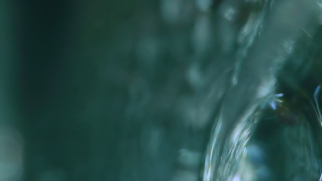 el agua dulce clara corre rápido en un fondo oscuro y borroso