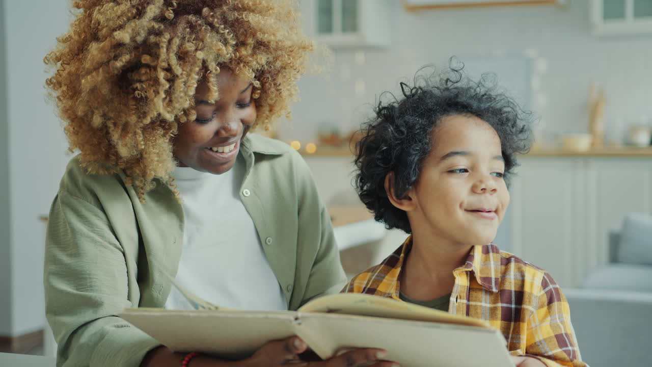 African American Mother Smiling and Reading Fairytale in Book with Little Son