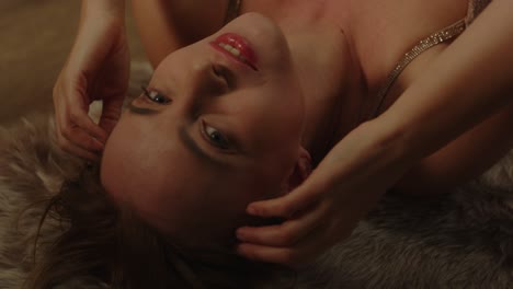 portrait of an attractive woman lying on a rug sensually caressing her face and moaning in pleasure