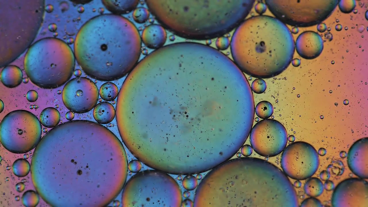 Bolle d'olio colorate iridescenti sull'acqua, sfondo macro astratto.