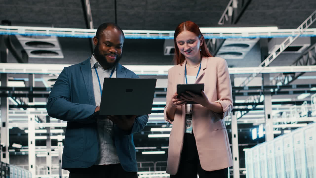 Tecnici IT che collaborano con laptop e tablet in un data center.