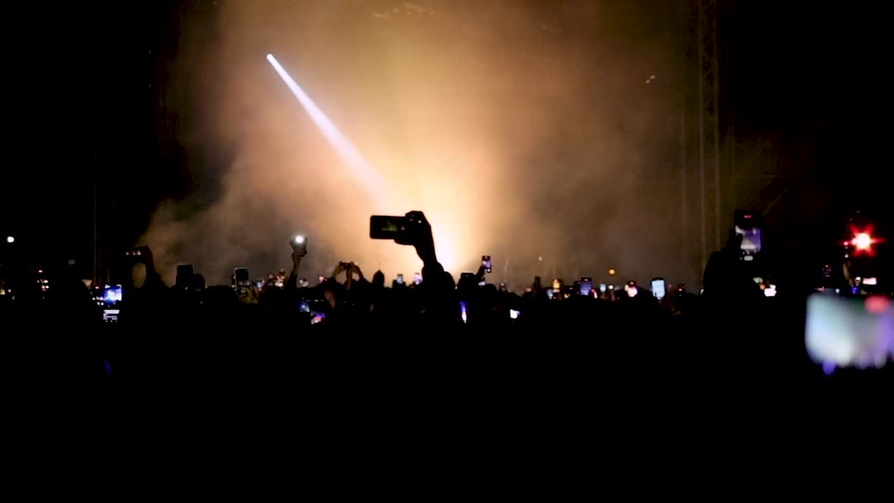 Crowd enjoying live performance and taking videos with smartphones