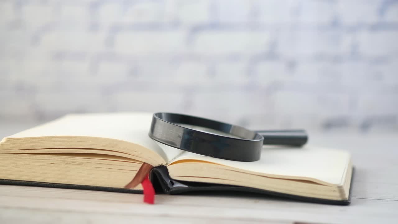 나무 테이블 에 확대 유리 를 가지고 열린 책