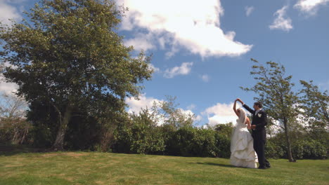 happy newlywed couple dancing in a park