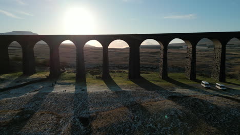 railway bridge archway fly-through at sunset in winter over moorland at ribblehead viaduct