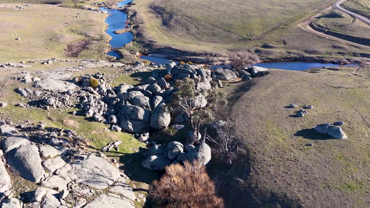 Droneskud af granitklippeformationer og en snoet bæk i landlige New South Wales
