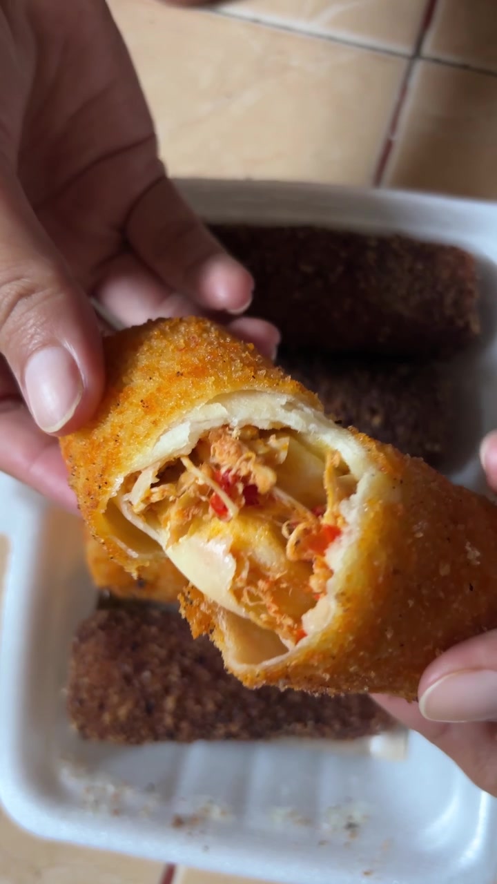 Mano che spezza un rissole fritto croccante con ripieno di pollo piccante