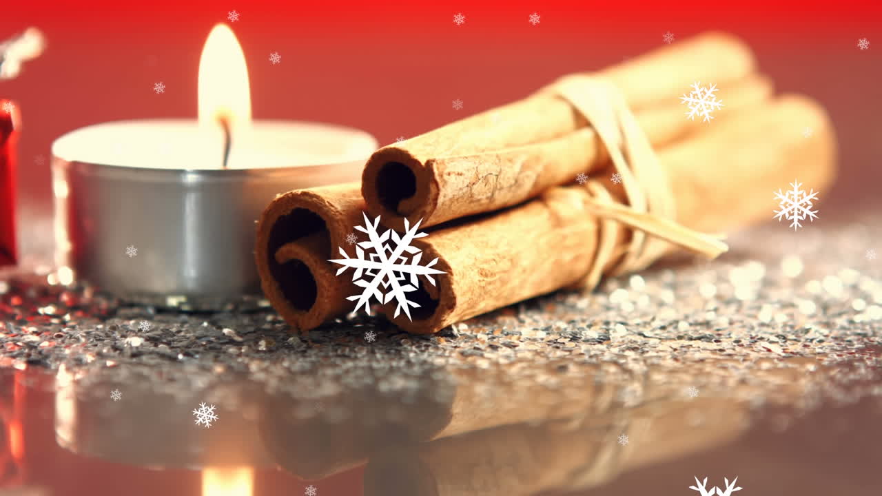 Digital composition of snowflakes falling against burning candle and cinnamon sticks