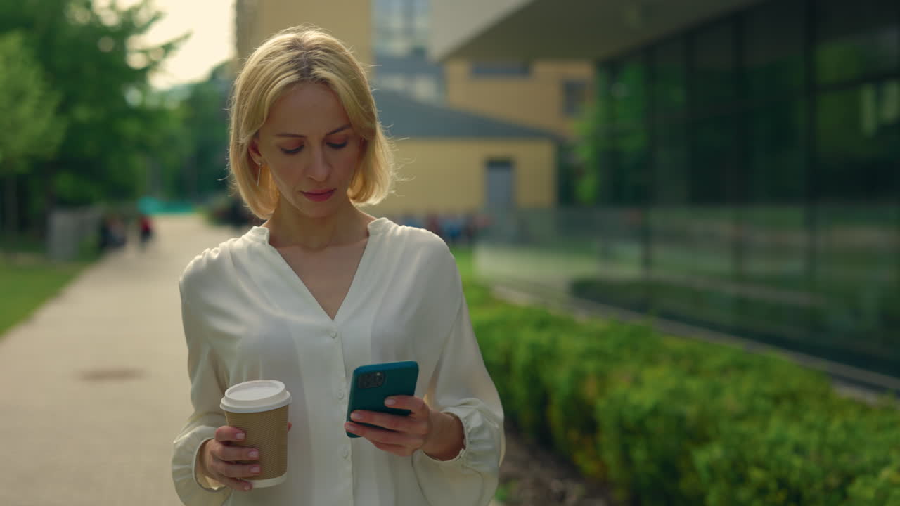 Woman walking and drinking coffee outdoors