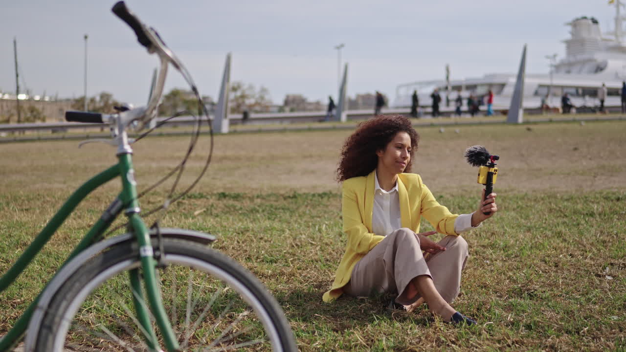 Woman vlogging outdoors with bicycle and cruise ship in background