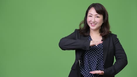 성숙하고 아름다운 아시아 사업가 여성이 무언가를 보여주고 있습니다.
