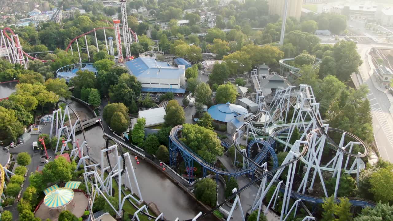 Sakte dolly-bevegelse fremover med drone som avslører en labyrint av berg-og-dal-baner og attraksjoner i fornøyelsespark