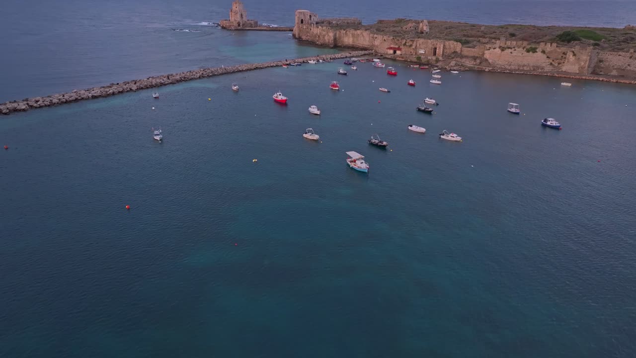 Dronefoto over Methoni slott og båter ved soloppgang
