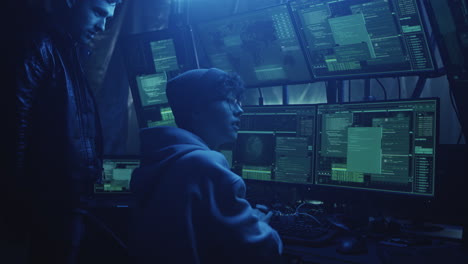 hackers or programmers working intently in a dark, blue-lit room with multiple computer monitors