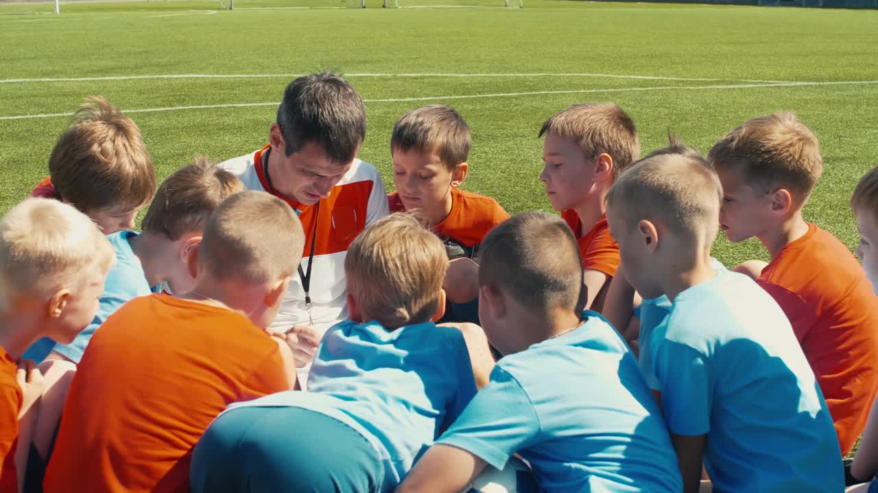 축구 코치 가 아이 들 에게 경기 의 계획 을 설명 하고 있다
