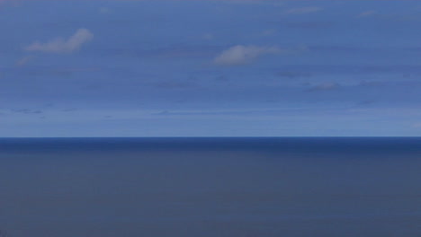 a calm blue sea sits under a blue sky