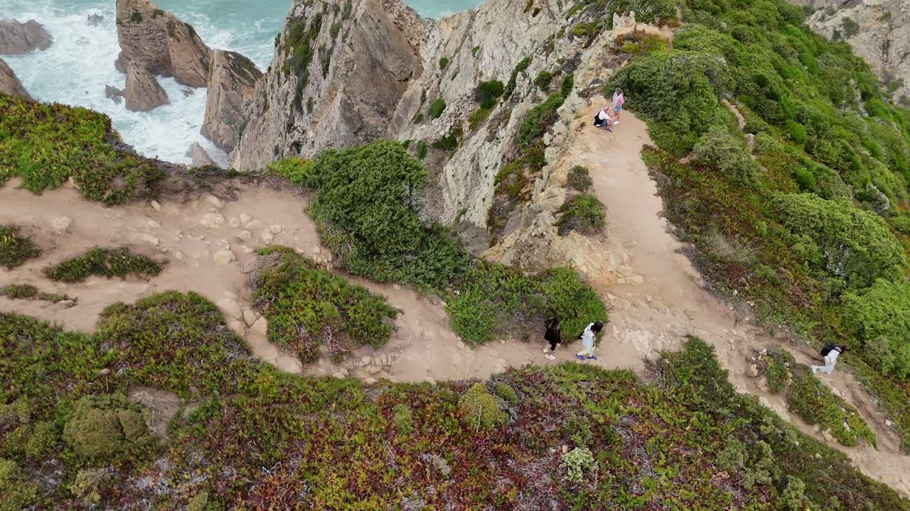 People Hiking on a Cliffside Path