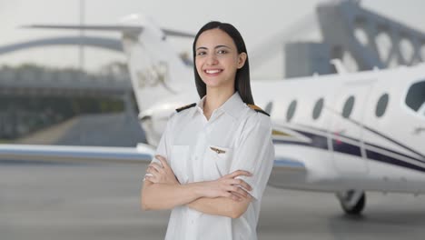 portrait of happy indian woman pilot standing crossed hands