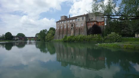 aerial shot over a lake and an old building in cassano d'adda in lombardy, italy