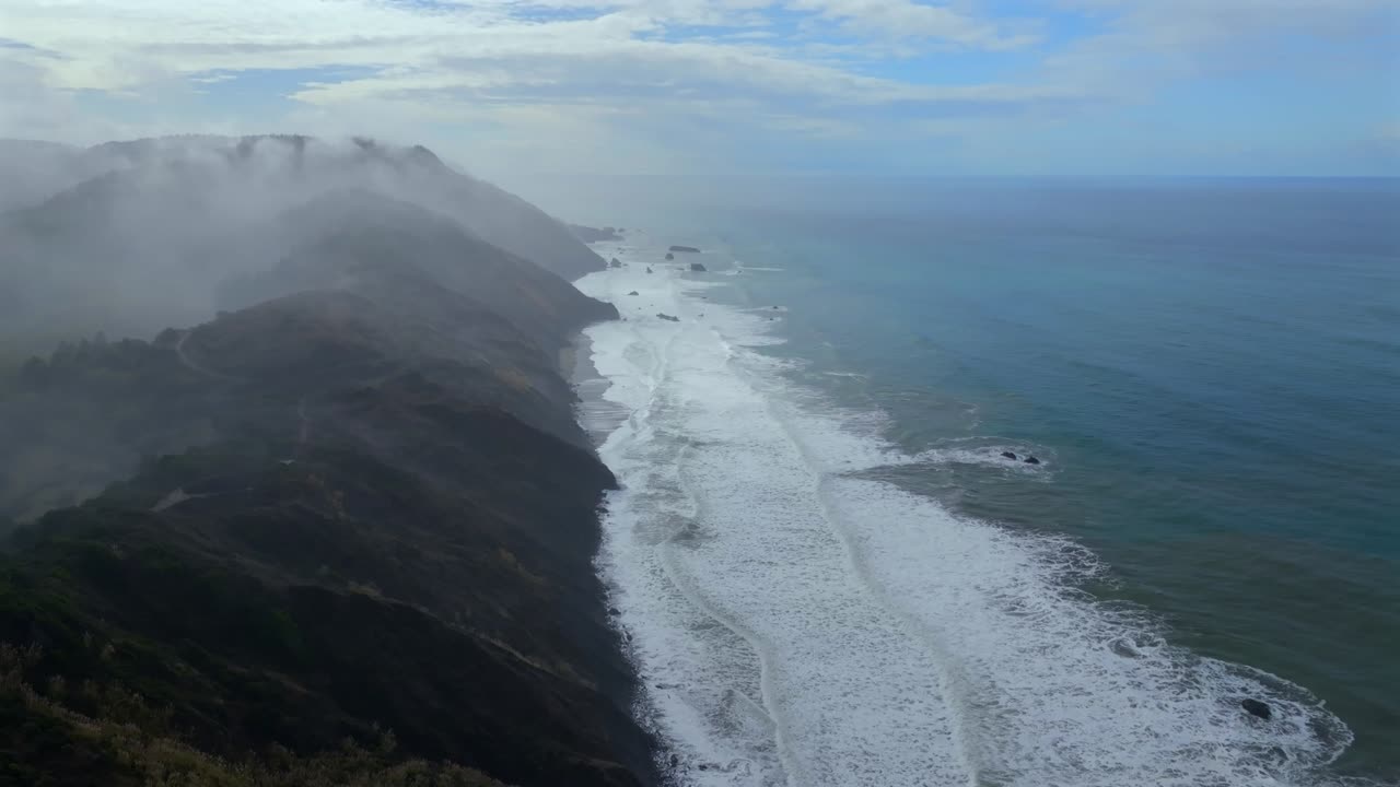 Rugged coastline Lost Coast Trail USAL Beach campground 4wd black sand mist rain fog aerial drone California PNW sun rays waves crashing cloud layer morning Chimney Rocks circle right