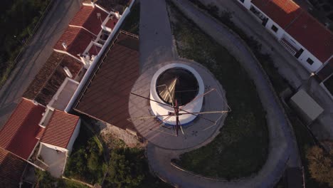 Reveal-shot-of-old-white-windmill-at-Odeceixe-Portugal-during-sunrise,-aerial