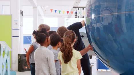 school kids using giant globe with teacher at science centre