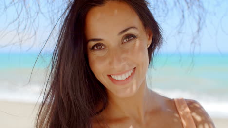 mujer alegre en la playa sonriendo a la cámara