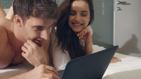 pareja sorprendida recibiendo correo electrónico portátil en la cama. pareja exitosa usando computadora