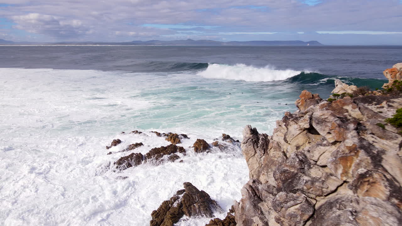 Atlantic ocean waves surge over coastal rocks on coastline, frothing seawater